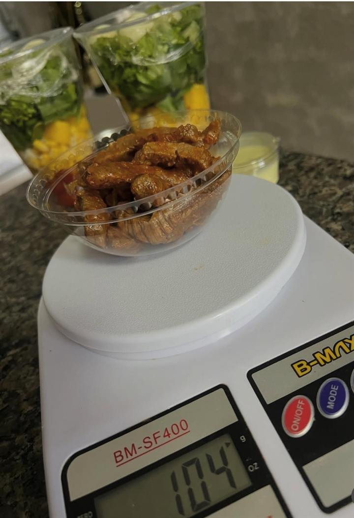 Porção de carne sendo pesada na balança, marcando 104 gramas